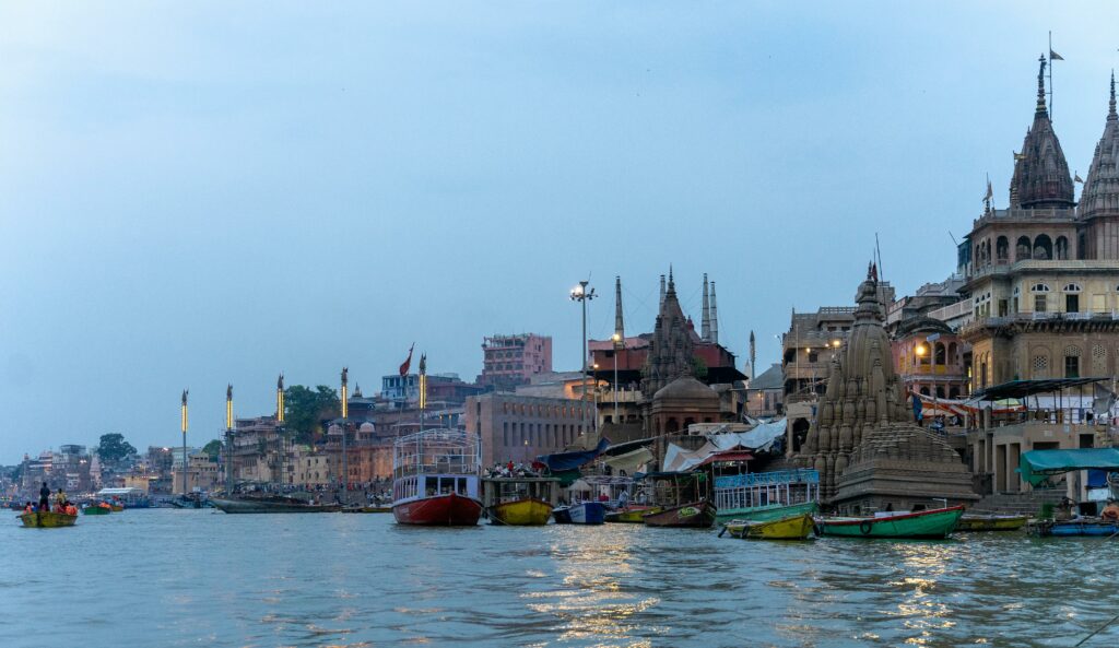 Explore the vibrant ghats of Varanasi along the Ganges River, India, with colorful boats and historic temples.